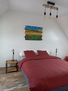 欧丹冈Le Repos du Randonneur的卧室配有红色的床和墙上的绘画