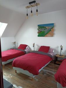 欧丹冈Le Repos du Randonneur的一间卧室配有两张带红色床单的床和墙上的绘画。