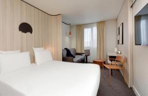 克莱蒙费朗Kyriad Clermont-Ferrand-Sud - La Pardieu的酒店客房带一张大床和一把椅子