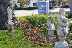 圣巴巴拉日落汽车旅馆的花园里的三座雕像,花朵和酒店标志