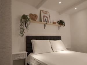 威廉斯塔德KDF公寓的一间卧室配有白色床单和植物床