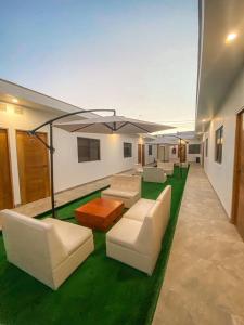 帕拉卡斯Nakua Paracas Lodge的客厅配有白色家具和绿色草地。