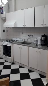 布宜诺斯艾利斯TANGO GUAPO APART的厨房配有白色橱柜和黑白格子地板。