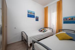 里耶卡Naval apartment的配有2张床的白色墙壁和橙色窗帘