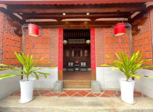 金宁乡金門古寧歇心苑官宅古厝民宿 Guning Xiexinyuan Historical Inn的两株白花瓶中的植物,在建筑物前