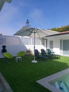 拉夫拉Lavra Beach House的一个带椅子和遮阳伞的草坪和一个游泳池