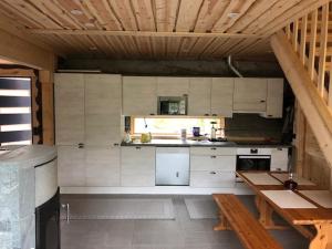 科拉里Kojamopirtit的厨房配有白色橱柜和木制天花板