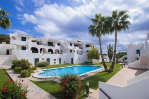 桑帕克Apartamento Albatros-Son Parc Menorca的一座带游泳池和棕榈树的大型白色房屋