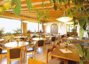 阿尔卑斯休斯山皮科洛希里亚酒店的餐厅设有桌椅和大窗户。