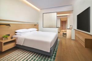 景德镇景德镇陶溪川凯悦嘉轩酒店的卧室配有白色的床和平面电视。