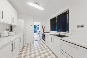 伦敦Stunning house的厨房配有白色橱柜和 ⁇ 格地板