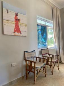 帕杰Paje Beach Apartments & Hotel的用餐室配有椅子和墙上的绘画作品