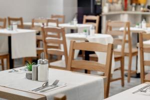 布拉格康特皇家酒店的用餐室配有白色的桌子和木椅