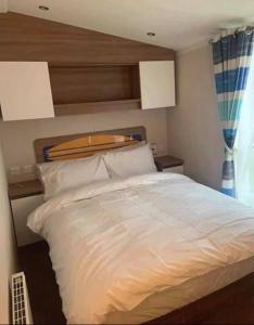英戈尔德梅尔斯8 Berth,Waterside Leisure,Ingoldmells的卧室配有白色的床和木制床头板
