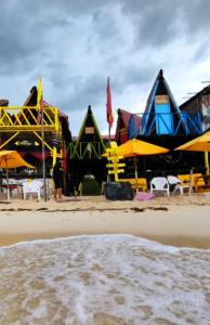 布兰卡滩Posada Tipiland la casa del Mono的海滩上一群配有椅子和遮阳伞的建筑