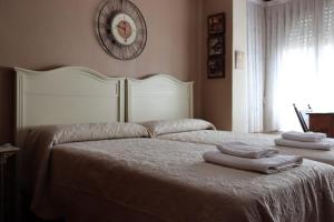 洛格罗尼奥La Esquina de Castroviejo的一间卧室设有两张床,墙上挂着一个时钟。