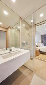 江陵市Skybay Hotel Gyeongpo的一间带水槽和淋浴的浴室以及一张床
