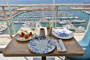 阿利坎特Hotel Alicante Gran Sol, affiliated by Meliá的一张带食物盘的木桌,享有海港的景色