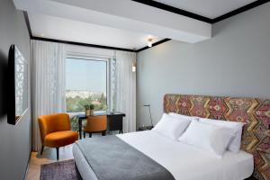 耶路撒冷Bat Sheva Jerusalem by Jacob Hotels的一间卧室配有一张床、一张书桌和一个窗户。