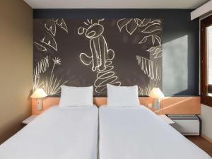 沙勒罗瓦沙勒罗瓦机场布鲁塞尔南宜必思酒店的一间卧室设有两张床,墙上挂着画图