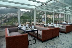 西姆拉The Orchid Hotel Shimla的餐厅配有沙发、桌子和窗户