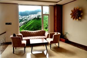 西姆拉The Orchid Hotel Shimla的客厅配有沙发、两把椅子和大窗户