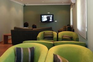 托沙阿卡达酒店的一间设有绿色椅子和平面电视的等候室