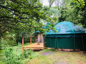斯托尔河畔希普斯顿Cotswolds Camping at Holycombe的河边的帐篷,设有木甲板