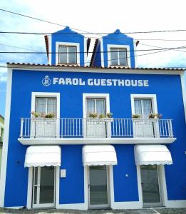 英雄港Farol Guesthouse的蓝色的建筑,设有白色的窗户和阳台