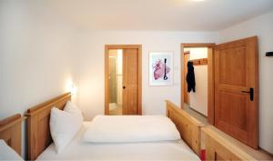 塞斯托Almrausch Apartments的卧室配有白色的床和木门