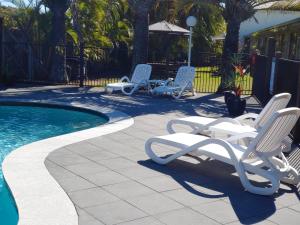 马库拉太平洋棕榈莫泰饭店的两把躺椅和一个位于庭院的游泳池