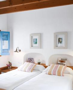 圣费兰-德瑟斯罗Can Xicu Castello的卧室设有两张床,拥有白色的墙壁和木制天花板