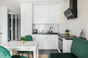罗兹ApartHouse Deluxe的厨房配有白色橱柜和白色的桌椅