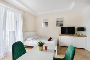 罗兹ApartHouse Deluxe的白色的客房配有一张床、一张桌子和椅子