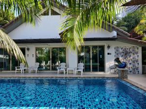 奈扬海滩The Snug Airportel - Phuket Airport的一个带椅子的游泳池以及一座房子