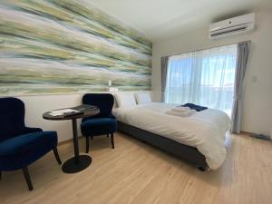 石垣岛HOTEL Ishigakijima 2020的酒店客房带一张床、一张桌子和椅子