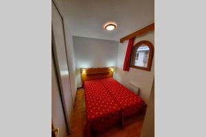 阿尔维厄Appartement en plein coeur du Queyras - Les Granges d'Arvieux的一张红色的床,位于一个小房间里,配有镜子