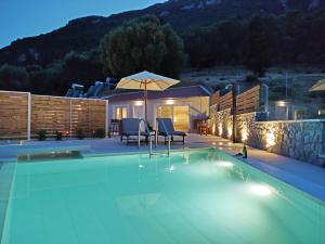 贝尼蔡斯Sea & Cliff Luxury Suites的一个带两把椅子和遮阳伞的游泳池