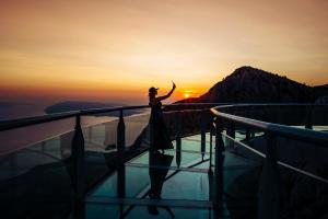 伯德古拉地中海酒店的日落时站在观景台边缘的女人