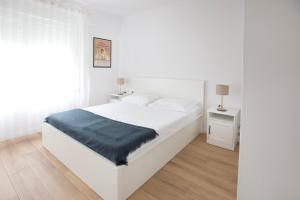 维斯Firpo: Cozy double room city centre apartment的白色卧室配有白色的床和蓝色毯子