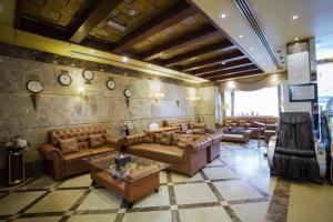 沙迦Crystal Plaza Hotel的客厅配有沙发、桌子和墙上的时钟