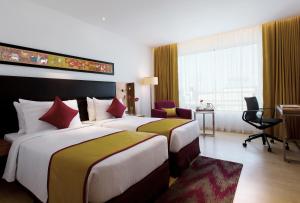 海得拉巴Mercure Hyderabad KCP Banjara Hills, An Accor Hotel的酒店客房配有两张床和一张书桌