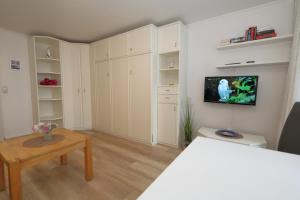 韦斯特兰Haus-am-Meer-App-71的客厅配有白色橱柜和墙上的电视