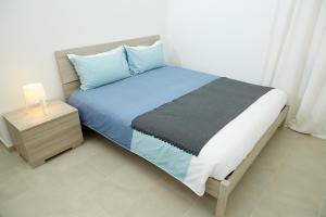 布林迪西Scirocco Guest House的一间卧室配有一张带蓝色床单的床和床头柜。