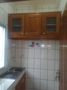 克里比NPANGOU APPART的厨房配有木制橱柜和白色瓷砖