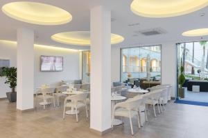 阿尔库迪亚港Trendhotel Alcudia - Adults Only的一间设有白色桌子和白色椅子的餐厅