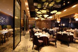 天津唐拉雅秀天津酒店的餐厅设有白色的桌椅和吊灯。