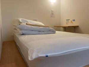 弘前市HOSTEL HIROSAKI -Mixed dormitory-Vacation STAY 32012v的一张带白色床单和枕头的床