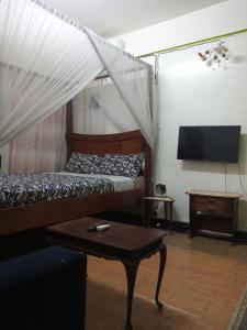 蒙巴萨SAFI Apartment的一间卧室配有一张床、一台电视和一张桌子