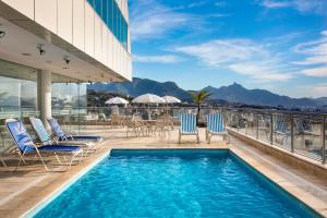 里约热内卢Windsor Asturias Hotel的阳台的游泳池,配有桌椅